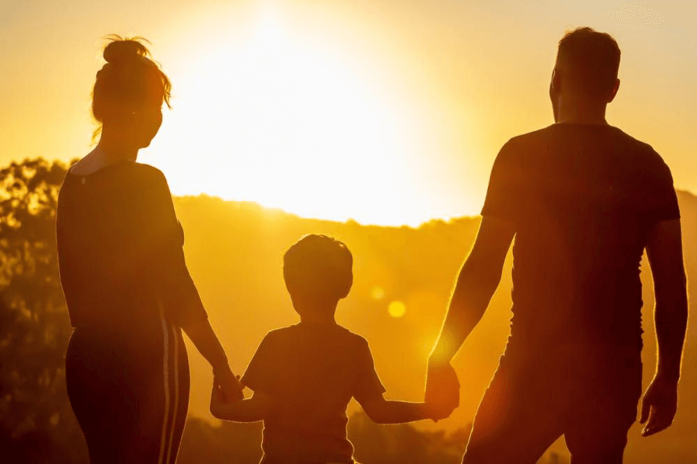 A husband, wife, and child looking at the sunset.