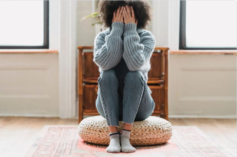 This is an image of a person sitting down with their face in their hands in anger.