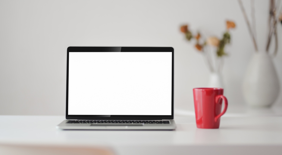 This is an image of a laptop on a table with a cup of coffee.