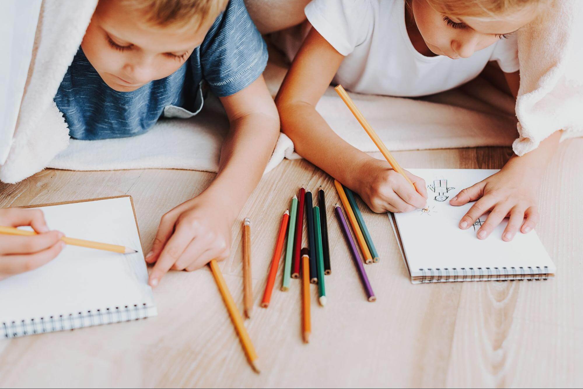 This is an image of two siblings drawing on paper together.