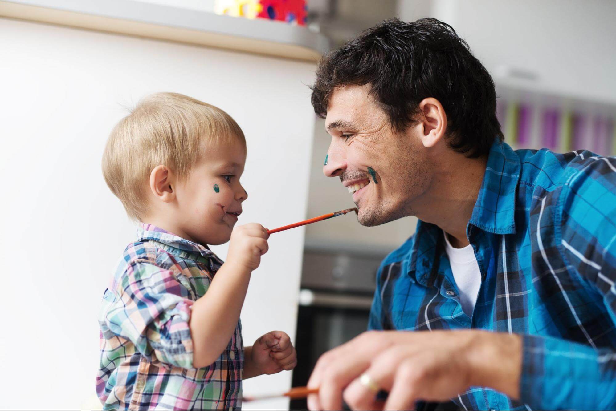 This is an image of a father and son playing with paintbrushes together.