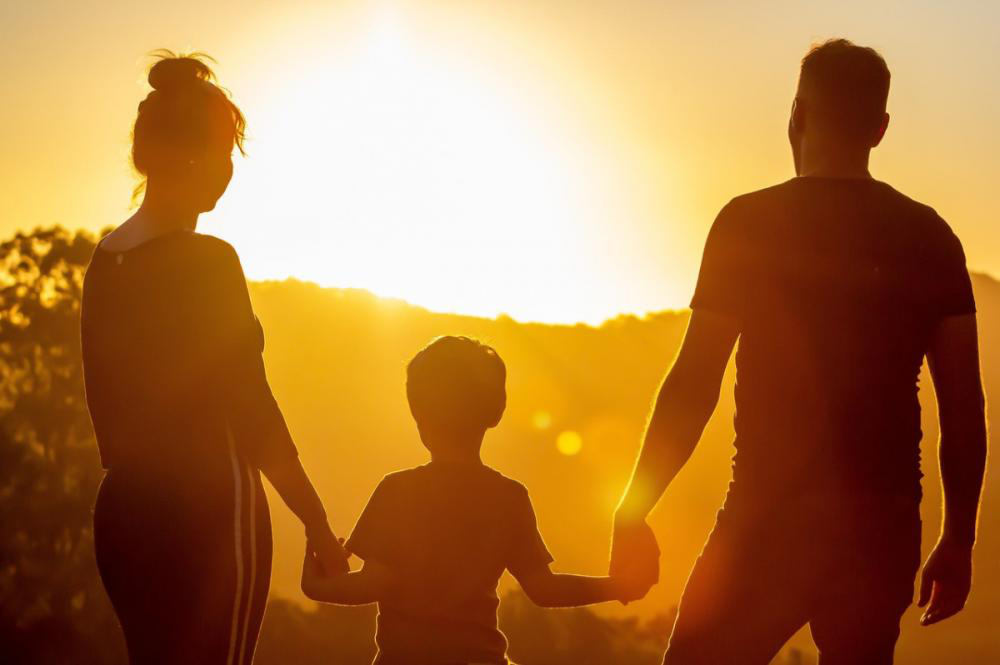 A husband, wife, and child looking at the sunset