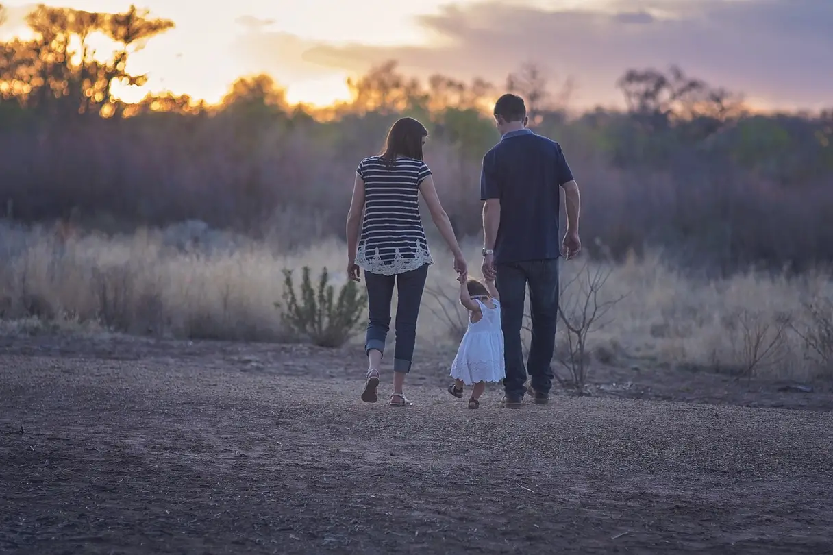 This is a photo of two parents walking with their child.