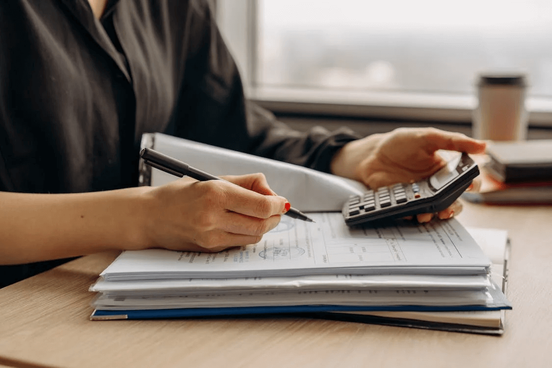 Person with a calculator and a pen writing on paper