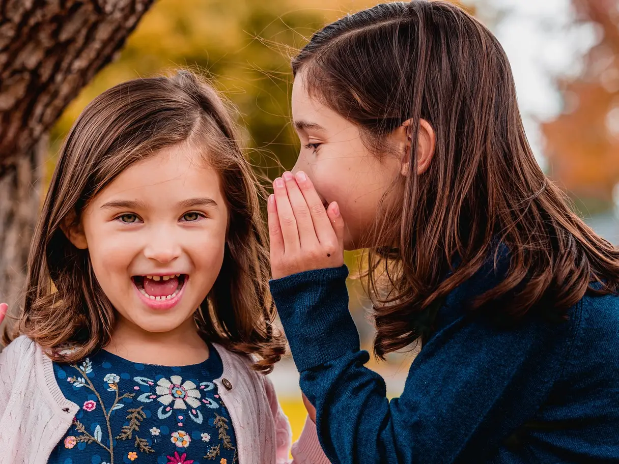 This is a photo of one sister whispering to another.