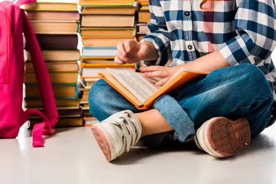 This is an image of a child sitting and reading a book.